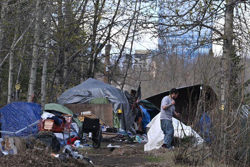 A person rakes at a homeless camp at the corner of Fireweed Lane and Arctic Boulevard on Tuesday, May 7, 2024. (Bill Roth / ADN)