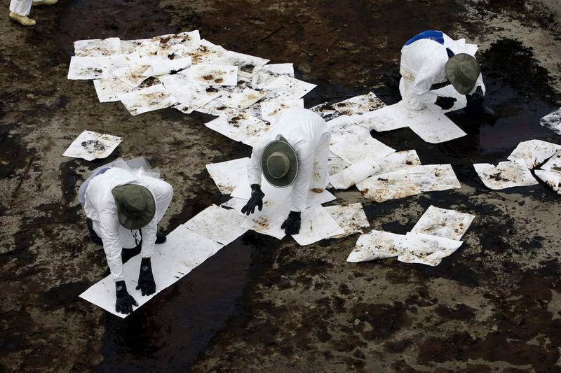 FILE - Workers use absorbent pads to remove oil that has washed ashore from the Deepwater Horizon spill, June 6, 2010, in Grand Isle, La. When a deadly explosion destroyed BP's Deepwater Horizon drilling rig in the Gulf of Mexico, tens of thousands of ordinary people were hired to help clean up the environmental devastation. (AP Photo/Eric Gay, File)