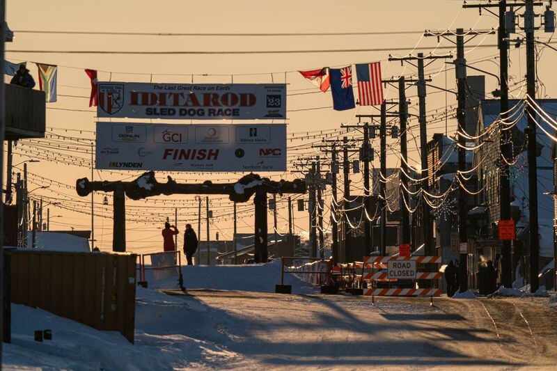 The sun rises over Front Street and the burled arch at the finish of the Iditarod Trail Sled Dog Race on March 15, 2023 in Nome. (Loren Holmes / ADN)
