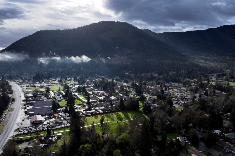 A vehicle at left drives down Rogue River Highway as light shines on the area Saturday, March 23, 2024, in Grants Pass, Ore. (AP Photo/Jenny Kane)