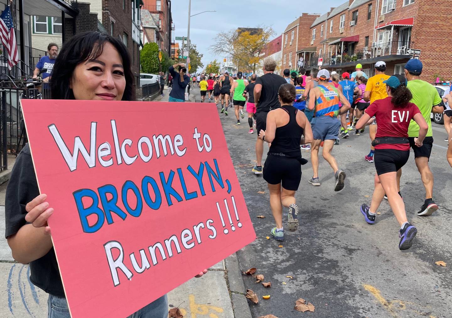 A woman welcomes runners to Brooklyn during the New York City Marathon