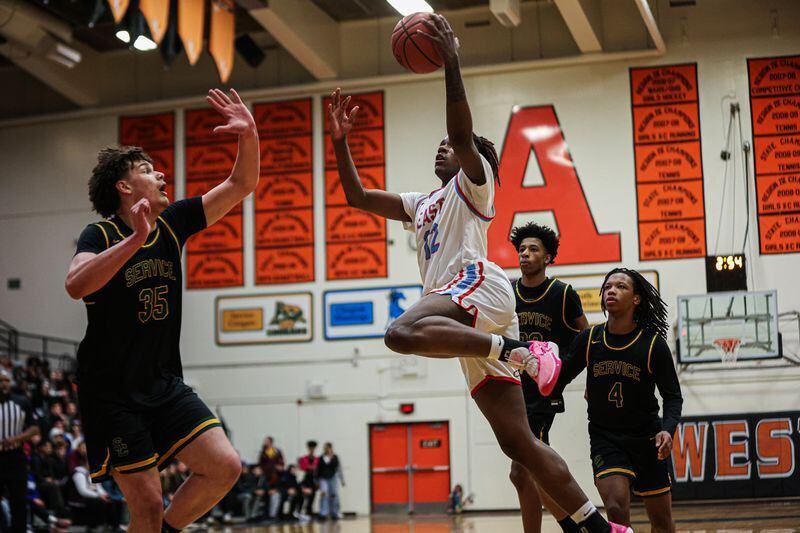 Bettye Davis East Anchorage's Akeem Sulaiman (12) drives into the post for a layup with Service's Toby Howard defending in the Thunderbirds' 58-41 win over the Cougars in the boys Region IV championship game on March 9, 2024, at West Anchorage high school. (Photo by Stephanie Burgoon)