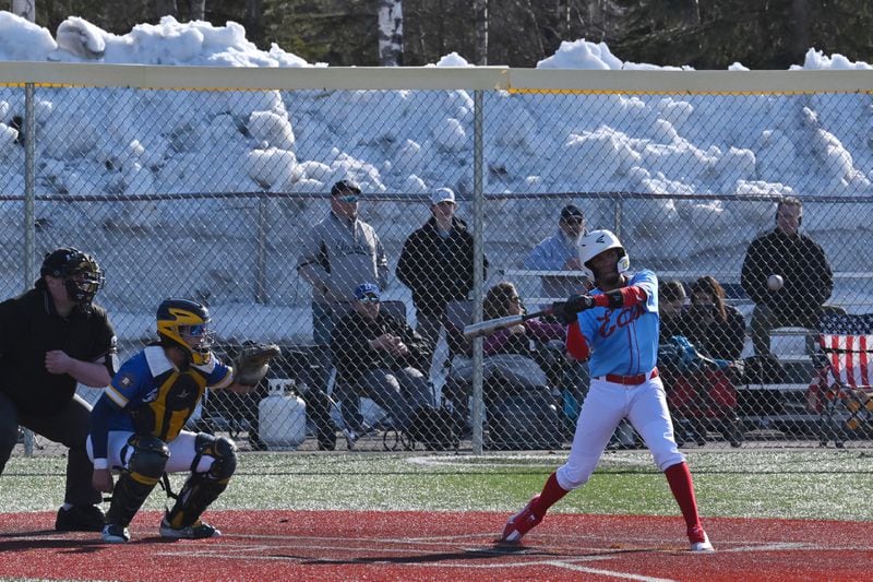 East High senior Juan Franco hits a double during a game against Bartlett with piles of snow behind the baseball field at Bartlett High School on Monday. The Thunderbirds defeated the Golden Bears 12-4. (Bill Roth / ADN)