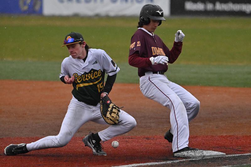 Service first baseman Owen Hickman attempts to catch a throw as Dimond baserunner Dylan Woodworth makes it back to the bag safely  Wednesday evening. (Bill Roth / ADN)