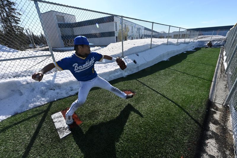 Snow lines the bull pen at Bartlett High School as Golden Bears starting pitcher freshman TJ Esahu warms up before a home game against the East High Thunderbirds on Monday, April 15, 2024. (Bill Roth / ADN)
