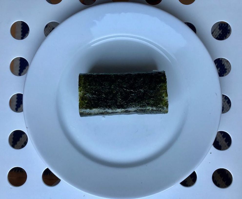 Step 5: Roll the musubi in nori seaweed. (If you can’t find hand-roll size seaweed, cut it to the width of the mold with sharp scissors.) Immediately wrap in Saran to soften the seaweed. (Julia O’Malley/ADN)