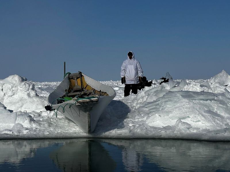A whaler stands near Russell Lane's umiaq in Point Hope. (Photo by Guy Omnik)
