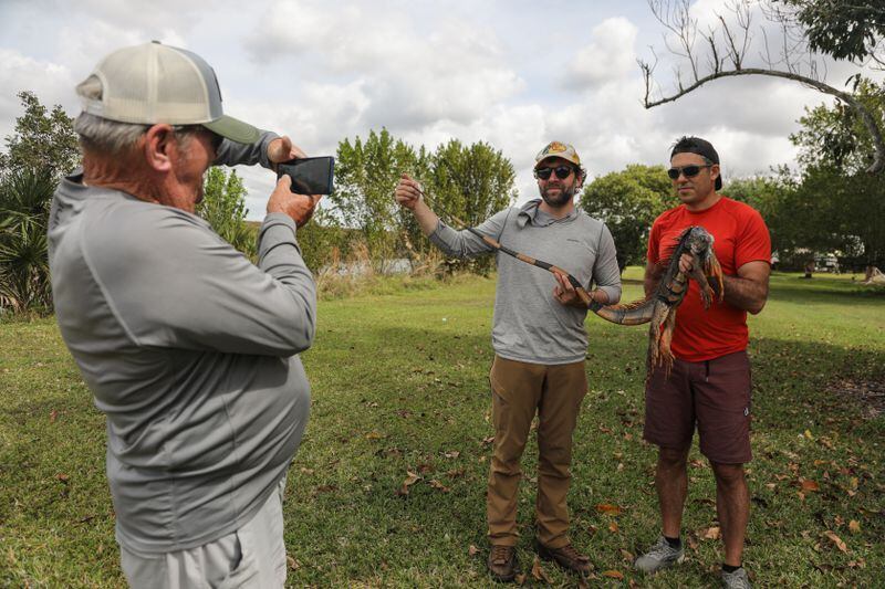 Captain Bud takes a picture of Zack and Michael as they hold a dead iguana. (Cindy Karp for The Washington Post)
