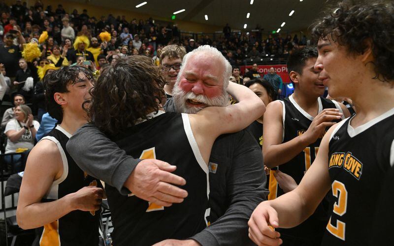 Michael Gould, of King Cove, hugs his head coach Kenneth Barbour at the end of the 1A boys state basketball championship game at the Alaska Airlines Center in Anchorage on Saturday, March 16, 2024. King Cove defeated Kake 39-31. (Bob Hallinen Photo)