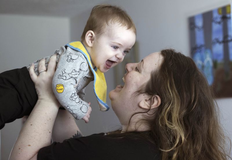 Nicole Slemp, a new mother of seven-month-old William, lifts up her son in their home, Thursday, March 14, 2024 in Auburn, Wash. (Ellen M. Banner/The Seattle Times via AP)
