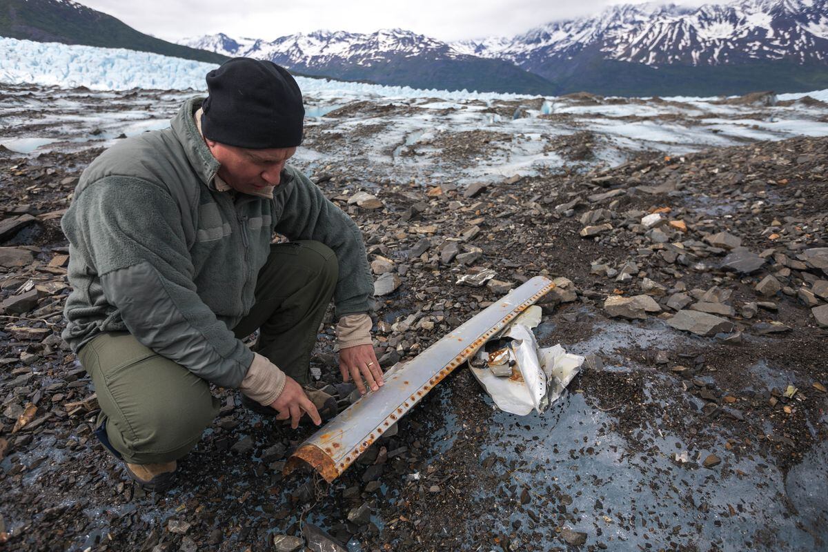 Col. Mark Schmidt, a pilot who flies F-15s and F-16s, examines a piece of debris, which he thinks is the leading edge of the plane, on Colony Glacier on Saturday. (Loren Holmes / ADN)