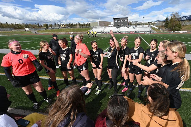South Anchorage goalie Skylar Lind, left, and her teammates huddle before the Wolverines 7-0 home shutout against the Bettye Davis East High Thunderbirds on Tuesday, May 7, 2024. (Bill Roth / ADN)