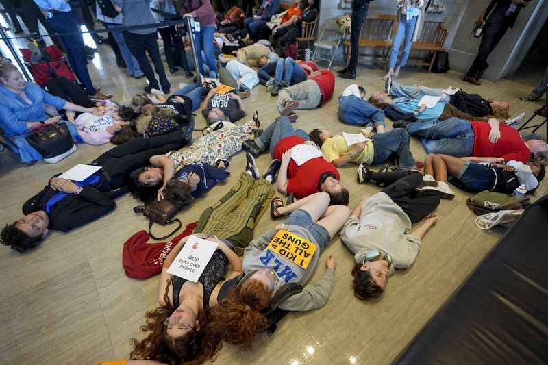 People perform a die-in during a demonstration against a bill allowing some teachers to be armed in schools on the House floor during a legislative session Tuesday, April 23, 2024, in Nashville, Tenn. (AP Photo/George Walker IV)