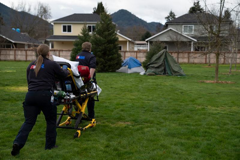 Emergency responders walk to a tent after a welfare check was called in by relatives on Saturday, March 23, 2024, in Grants Pass, Ore. The rural city of Grants Pass in southern Oregon has become the unlikely face of the nation’s homelessness crisis as its case over anti-camping laws goes to the U.S. Supreme Court. The case has broad implications for cities, including whether they can fine or jail people for camping in public. (AP Photo/Jenny Kane)