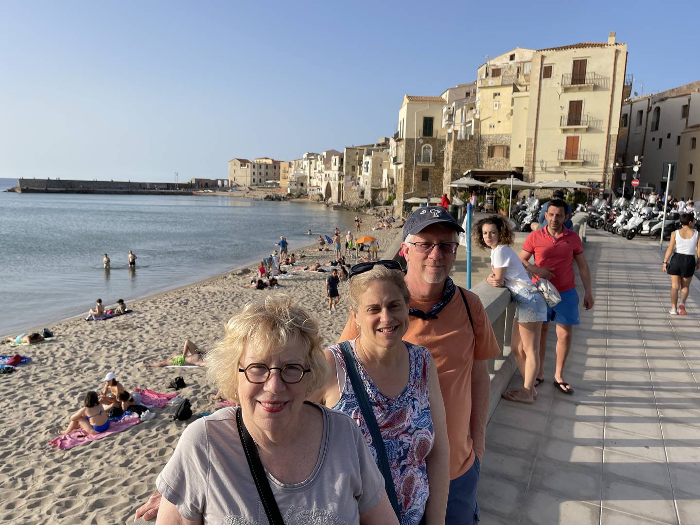 A group of travelers strolling along the beachfront in Cefalu, Sicily