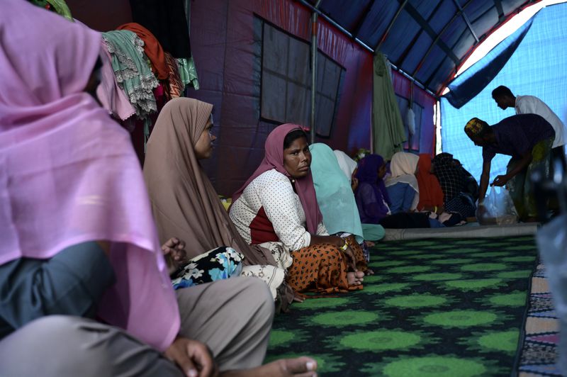 Rahena Begum, third from left, a survivor of a capsized refugee boat, sits with other ethnic Rohingya women at their temporary shelter in Meulaboh, Indonesia, on Thursday, April 4, 2024. In March, Indonesian officials and local fishermen rescued 75 people from atop the overturned hull of the boat. Dozens of other Rohingya refugees died. (AP Photo/Reza Saifullah)