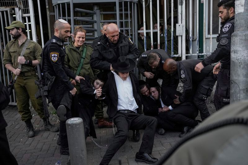 Israeli police officers scuffle with ultra-Orthodox Jewish men during a protest against possible changes to the military draft laws, outside a military recruitment office in Jerusalem, Monday, March 4, 2024. (AP Photo/Leo Correa)