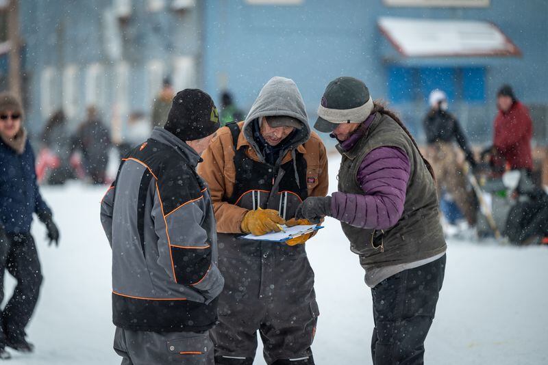 (From left) Elvin Wood and Kirk Sampson talk with Jessie Royer shortly after checking a musher into Noorvik. Photo by Whitney McLaren.