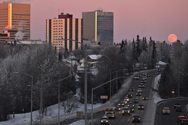 A full moon, known as a Wolf Moon, rises over Anchorage as rush hour traffic flows on Minnesota Drive on Thursday, Jan. 25, 2024. (Bill Roth / ADN)