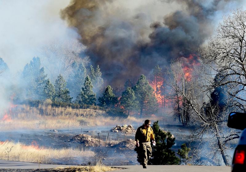 A firefighter walks up a road near a home at Middle Fork Road and Foothills Highway north of Boulder, Colo., on Thursday, Dec. 30, 2021. (Cliff Grassmick/Daily Camera via AP)