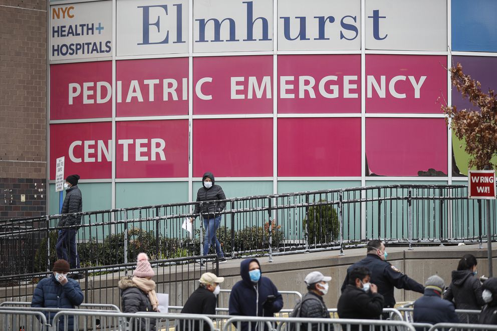 A woman exits a COVID-19 testing site while hundreds wait in line at Elmhurst Hospital Center, Wednesday, March 25, 2020, in New York. Gov. Andrew Cuomo sounded his most dire warning yet about the coronavirus pandemic Tuesday, saying the infection rate in New York is accelerating and the state could be as close as two weeks away from a crisis that sees 40,000 people in intensive care. Such a surge would overwhelm hospitals, which now have just 3,000 intensive care unit beds statewide. (AP Photo/John Minchillo)