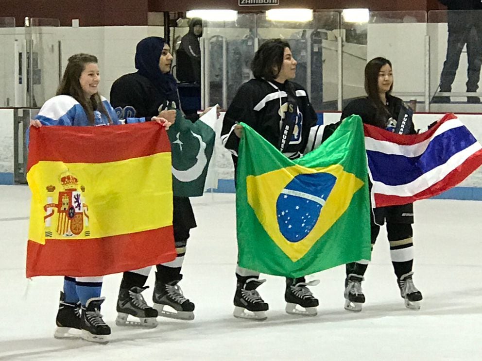 Four foreign exchange students stand at center ice during the Anchorage high school hockey league's Senior Night ceremony last week at Dempsey Anderson Arena. Holding their national flags are, from left, Alicia Prieto of Spain, Leena Tarar of Pakistan, Giulia Brunetta of Brazil and Jom Pukkanavanich of Thailand. (Beth Bragg / ADN)