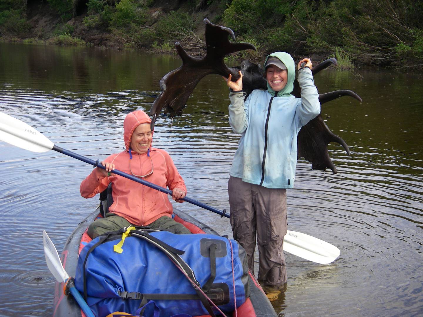 Molly Yazwinski holds a 3,000-year-old moose skull with antlers still attached, found in a river on Alaska’s North Slope. Her aunt, Pam Groves, steadies an inflatable canoe.