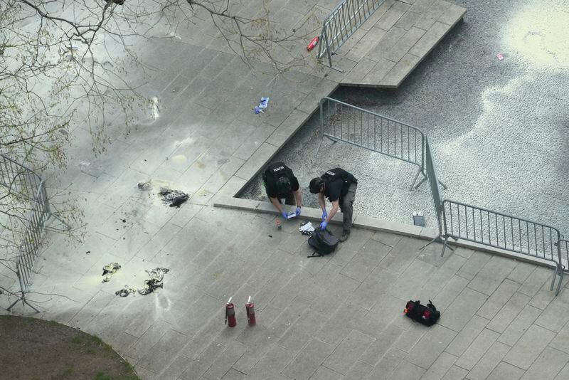 New York Police officers inspect a backpack left at the scene where a man lit himself on fire in a park outside Manhattan criminal court, Friday, April 19, 2024, in New York. (AP Photo/Mary Altaffer)